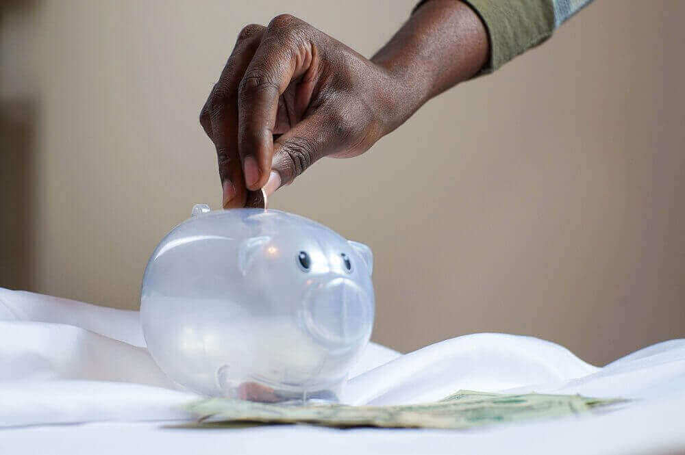 Person putting money into a piggy bank | Guide My Growth